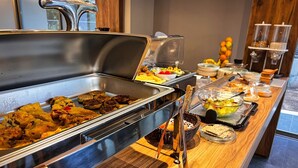 Un buffet proposant une variété de plats, notamment des viandes, des salades et des fruits.
