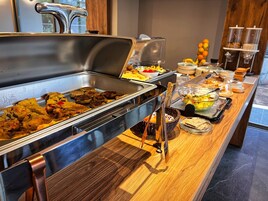 Un bufé con diversos alimentos, como carnes, ensaladas y frutas.