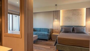 A modern bedroom with a large bed, a blue sofa, and a wooden accent wall.