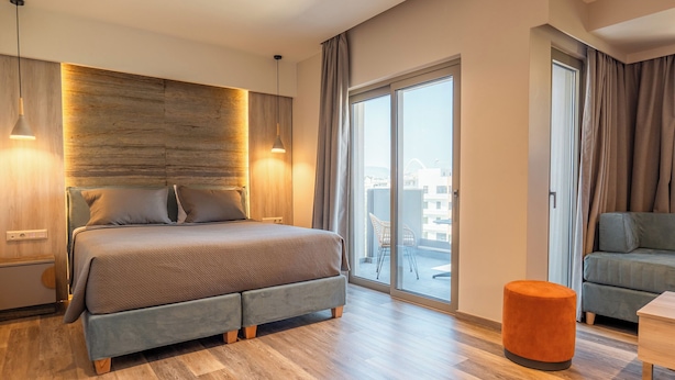 Une chambre moderne avec un grand lit, un canapé et un petit pouf orange.