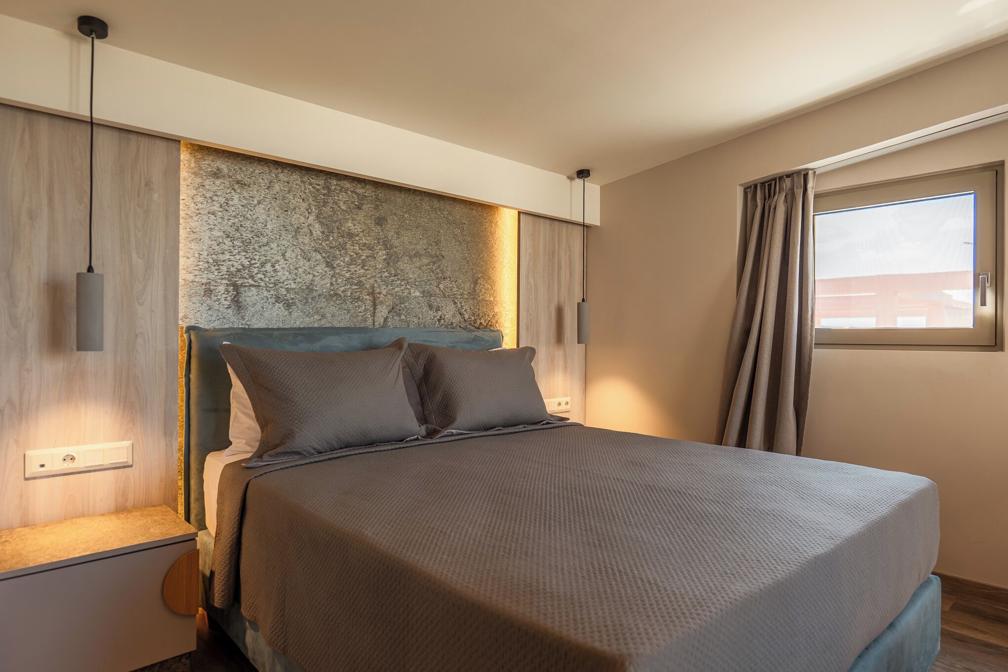 A modern bedroom with a large bed, a textured wall, and a window with curtains.