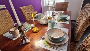 A dining table set with plates, bowls, and cups, surrounded by wicker chairs. - 120m², 6+1 Pers. 3 SZ / 4TV 100 Mbit/s +netflix (Arnsdorf)