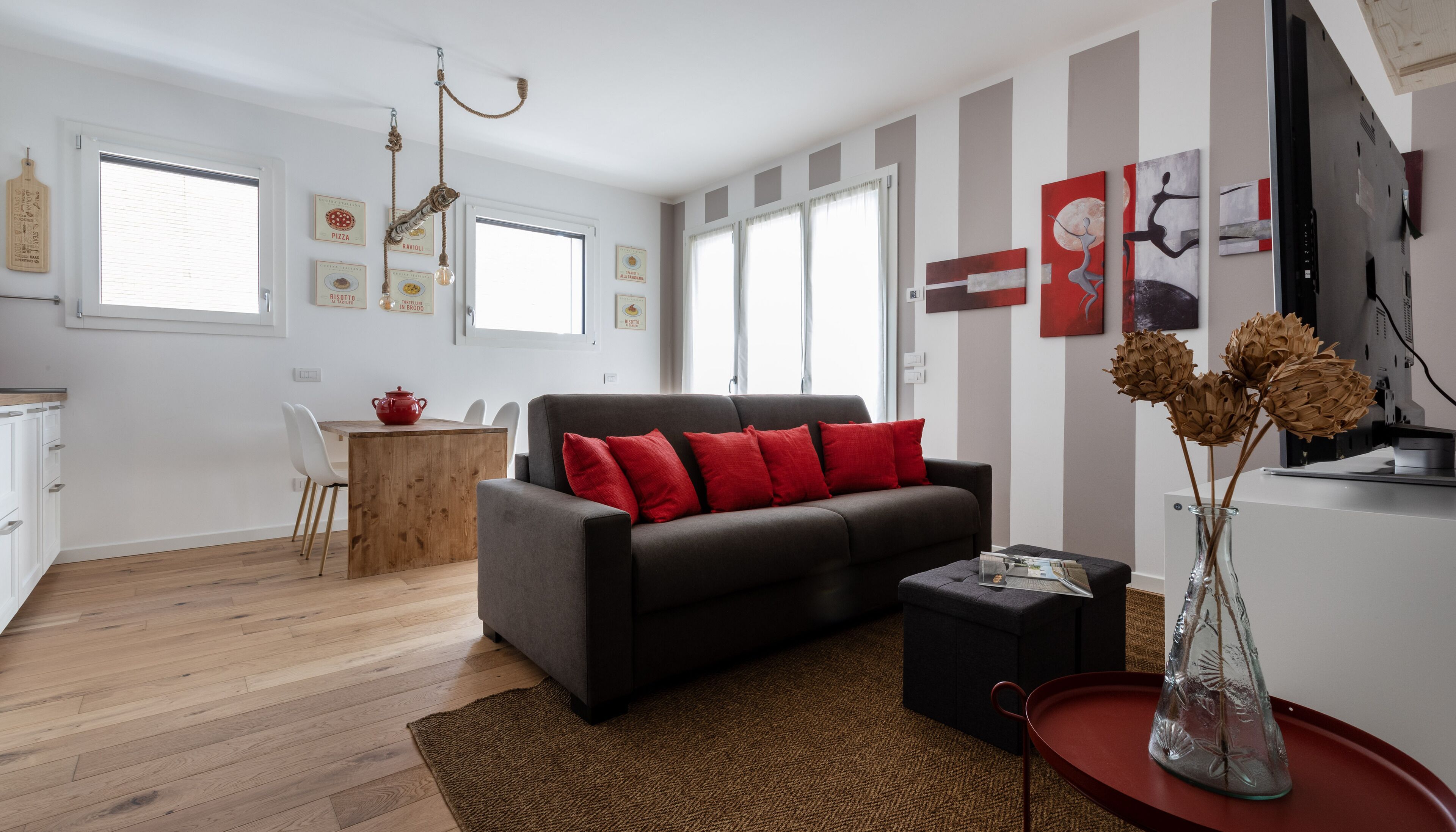 A modern living room with a sofa, a dining table, and a kitchen area.