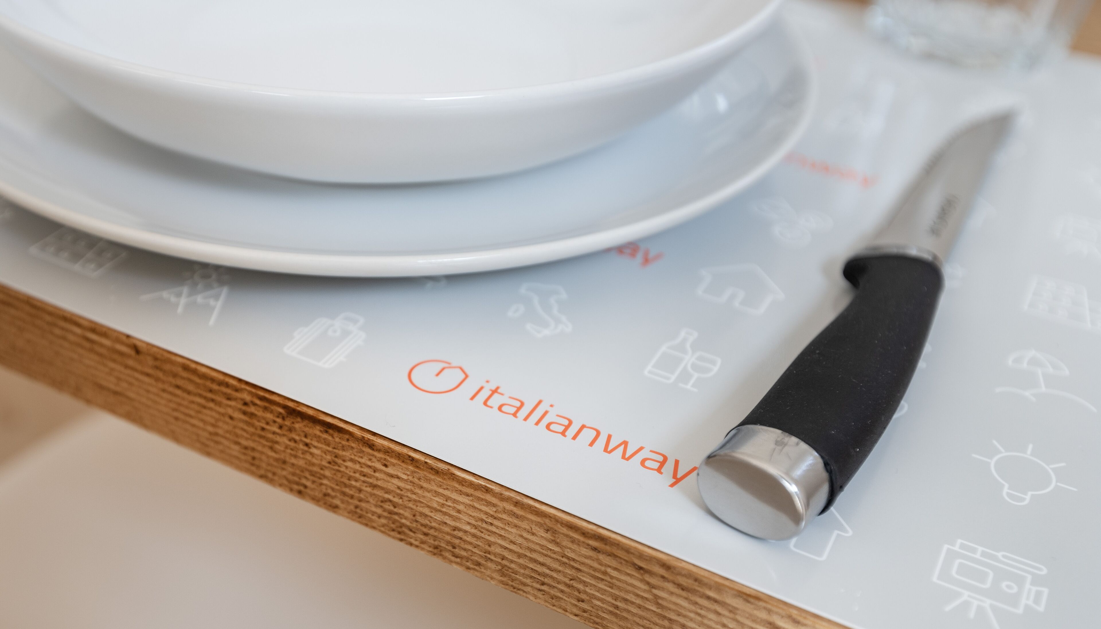 A kitchen counter with white plates, a knife, and a menu with icons.