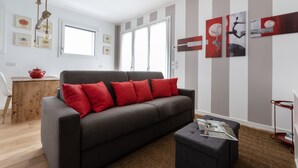 A modern living room with a grey sofa, red cushions, a wooden coffee table, and a striped wall. - Italianway - Piranesi 18 B int C345 - City View (Milan)