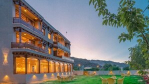 Un hotel de varios pisos con balcones y mobiliario exterior.
