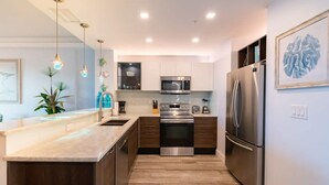 A modern kitchen with a central island, stainless steel appliances, and pendant lighting. - Waterfront Stateroom (Merritt Island)