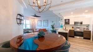 A modern kitchen with stainless steel appliances, a dining area with a round table, and a chandelier. - Waterfront Stateroom (Merritt Island)