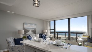 A modern kitchen with a large island, dining area, and a view of the ocean.
