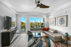 A modern living room with a sofa, coffee table, TV, and artwork on the walls. - Waterfront Captains Stateroom (Merritt Island)