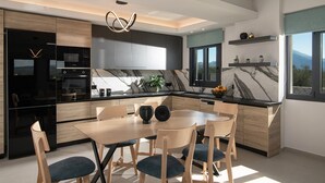 A modern kitchen with a marble countertop, wooden cabinetry, and a dining area with a table and chairs. - Pura Vida Villa, 2 Heated Pools, Hot Tubs & Sauna (Rethymno)