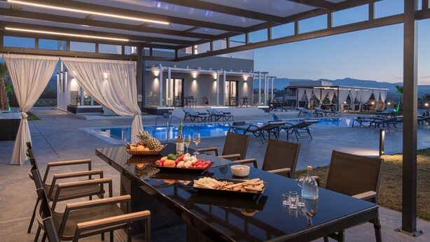 An outdoor dining area with a pool, dining tables, chairs, and a buffet with fruits and beverages. - Pura Vida Villa, 2 Heated Pools, Hot Tubs & Sauna (Rethymno)