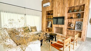 Een moderne woonkamer met een houten accentmuur, een witte bank, een salontafel en een aan de muur bevestigde televisie.