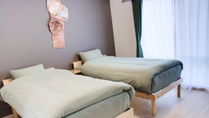 Two single beds with wooden frames in a room with light-colored walls and a wooden floor. - Island Stay Izumizaki Hotel (Naha)