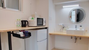A compact kitchenette with a microwave, refrigerator, and sink. - Island Stay Izumizaki Hotel (Naha)