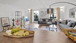 Ein modernes Wohnzimmer mit Couch, Holztisch und einem Essbereich mit Käseplatte.