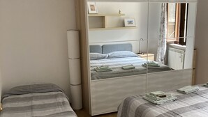 Une chambre avec deux lits, une armoire et un miroir.