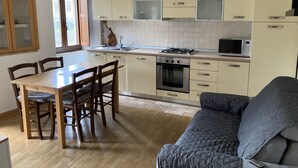 Une cuisine moderne avec des meubles en bois, une table à manger avec des chaises et un canapé gris.