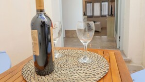 A bottle of wine on a woven mat with two glasses on a wooden table. - Casa Malika Space, Comfort & Mediterranean Charm in the Heart of Otranto (Otranto)