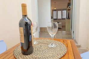 Une bouteille de vin posée sur un tapis tressé, avec deux verres sur une table en bois.