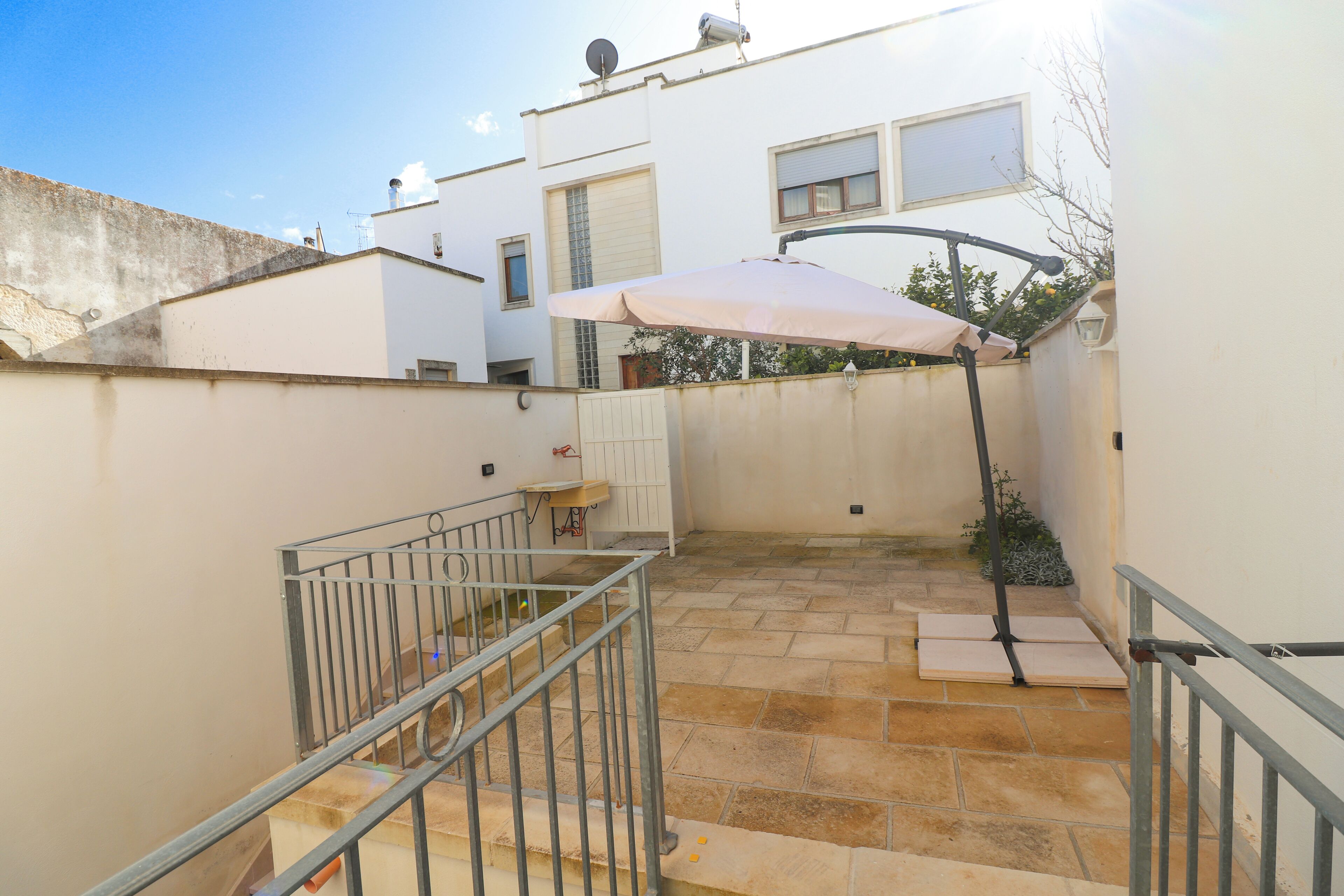A courtyard with a staircase, a metal railing, and a patio umbrella.