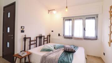 A bedroom with a bed, bedside table, and a window with curtains.