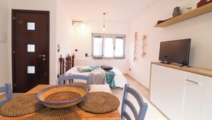 A room with a bed, a television on a cabinet, a door, and a window. - Casa Malika Space, Comfort & Mediterranean Charm in the Heart of Otranto (Otranto)