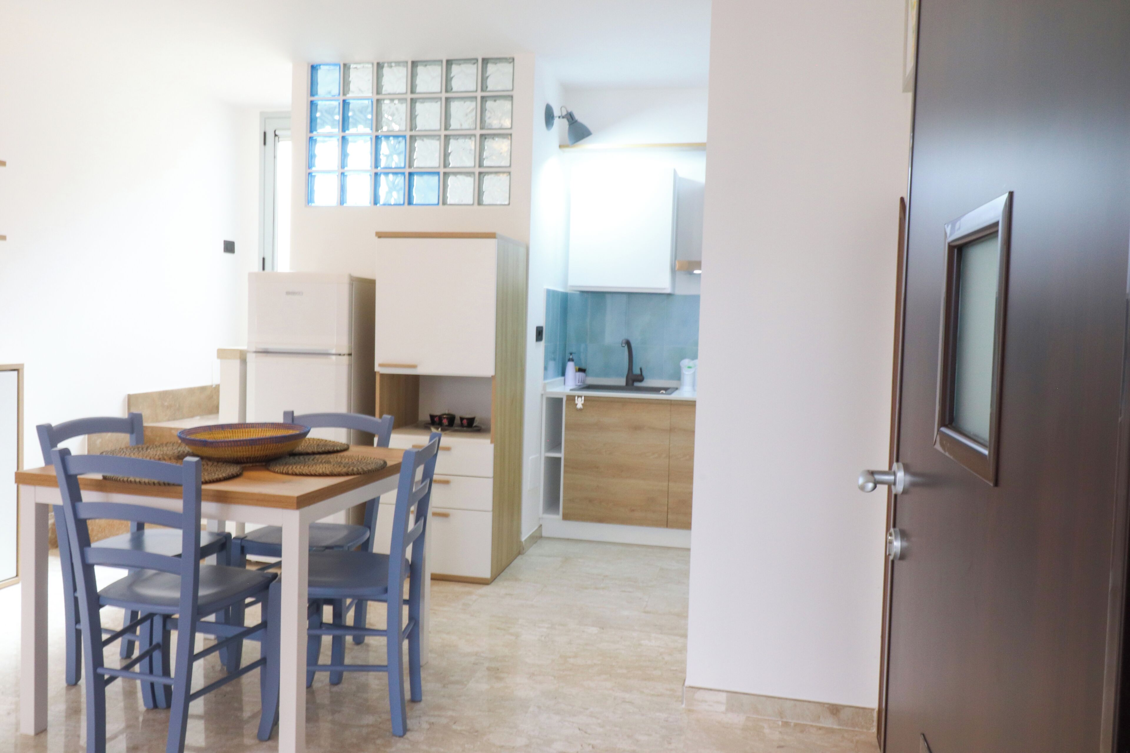 A compact kitchen with a dining area, featuring a refrigerator, sink, and cabinets.