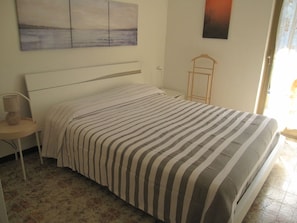Ein Schlafzimmer mit Bett, Nachttisch, Lampe und Fenster.