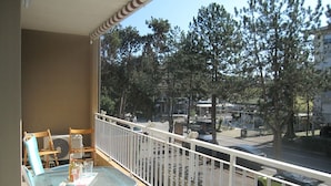 A balcony with a table and chairs, overlooking a street with trees and parked cars. - Enjoy the sun From our Lovely Terrace (Grado)