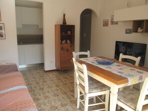 Ein Essbereich mit Tisch, Stühlen, einem Schrank und einem Fernseher.