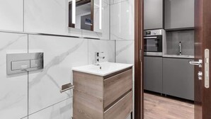 A modern bathroom with a marble wall, a wooden vanity, a sink, and a mirror.