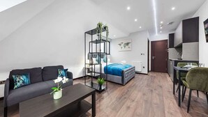 A modern apartment with a living area, a bedroom, and a kitchenette.