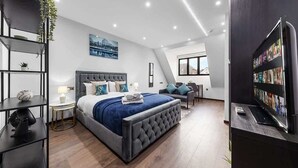 Ein modernes Schlafzimmer mit einem großen Bett, einem Fernseher und einem Bücherregal.