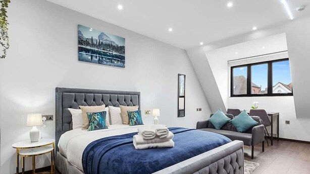 Ein modernes Schlafzimmer mit einem großen Bett, einem Schreibtisch und einem Fenster mit Blick.