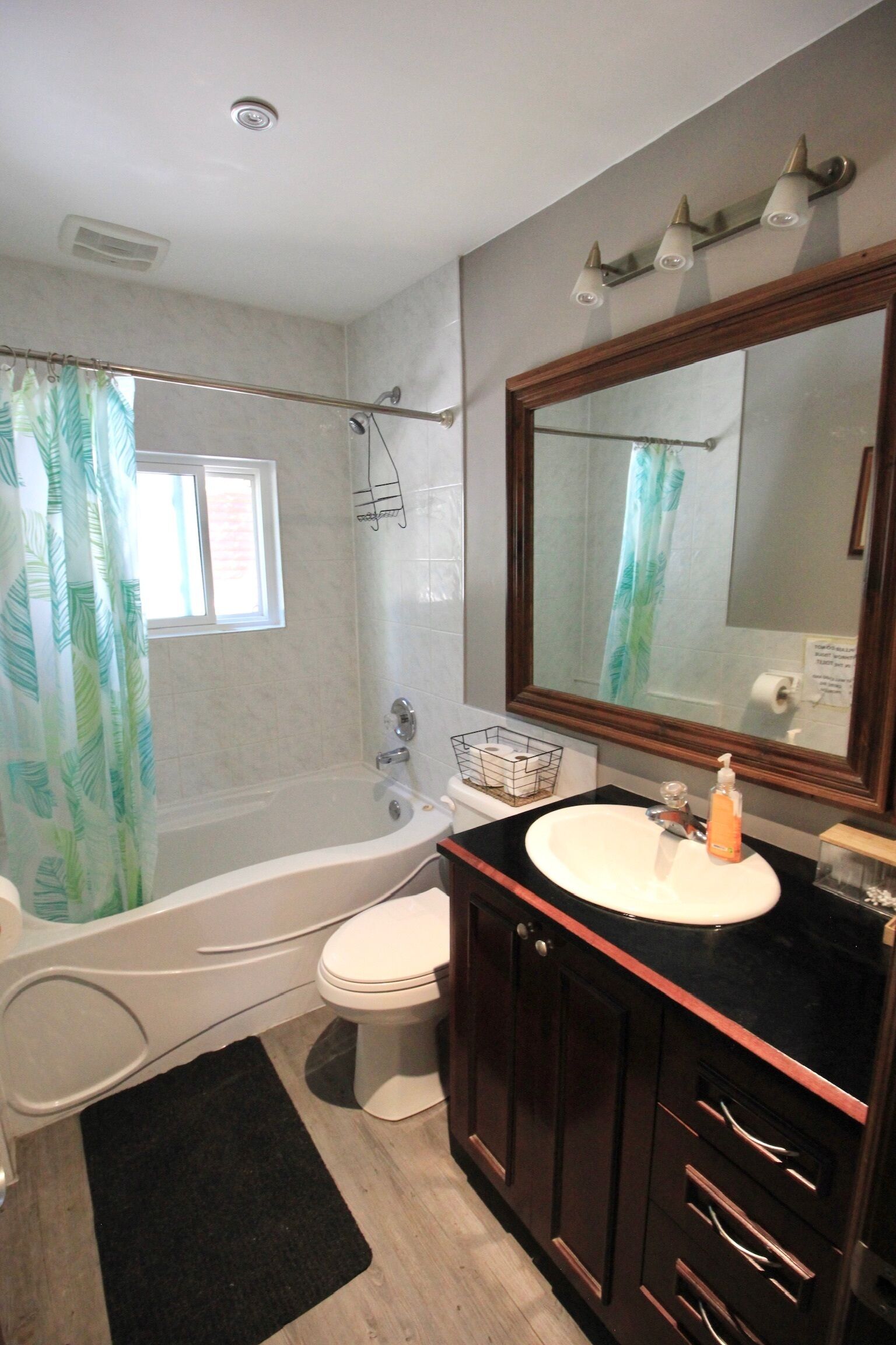 Ein Badezimmer mit Badewanne, Toilette, Waschtisch und einem großen Spiegel.