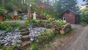 A rustic cabin with a wooden structure and a stone wall. - Discover Serenity: Ultimate Summer Getaway Awaits at Charming Cottage Retreat! (Bancroft)