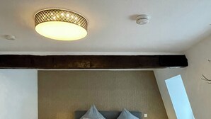 Une chambre moderne avec un lit, deux lampes de chevet, une grande fenêtre et un plafond en pente.