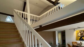 Un escalier avec des rampes blanches et des marches en bois menant à l’étage supérieur.