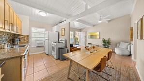 A modern kitchen with granite countertops, a dining area with a wooden table, and a ceiling fan.