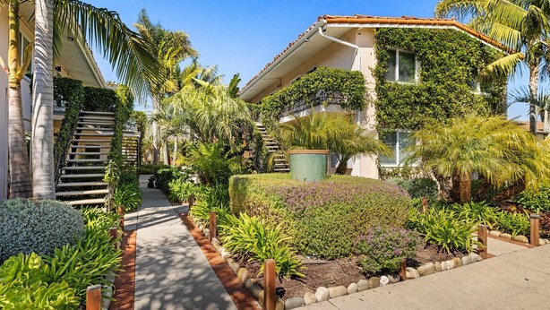 A residential building with a staircase, lush greenery, and a pathway.