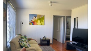 Un salon avec un canapé, un téléviseur, une petite table et un tableau accroché au mur.