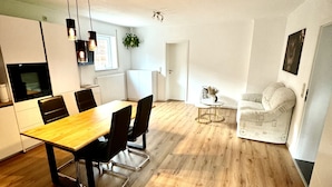 Eine moderne Küche mit Holzboden, einem Esstisch mit Stühlen und Pendelleuchten.