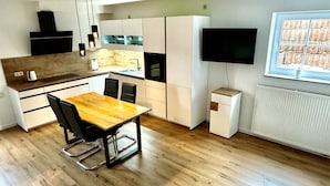 Eine moderne Küche mit einem Holzes Esstisch, schwarzen Stühlen und einem eingebauten Backofen.
