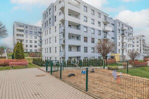 Un moderno edificio de apartamentos con varios balcones y un área de juegos cercada.