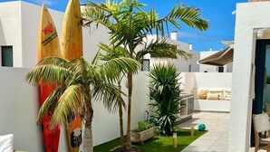A modern outdoor area with a pool, artificial grass, and a dining table. - Atemberaubende Villa Palmeral in Corralejo mit Whirlpool & Beheizten Privatpool (La Oliva)