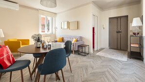 Una sala de estar moderna con comedor, un sofá, una mesa de centro y un bolso rojo en el suelo.