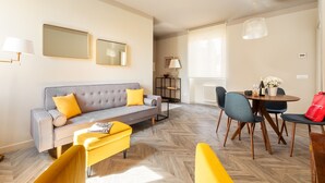 Una sala de estar moderna con un sofá, sillas, una mesa de comedor y una zona de cocina.