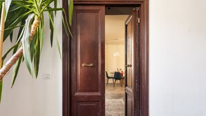 Puerta de madera que da a un comedor con suelo de espiga y una mesa dispuesta para dos personas.