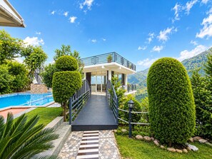 A two-story house with a balcony, a swimming pool, and a mountain view.